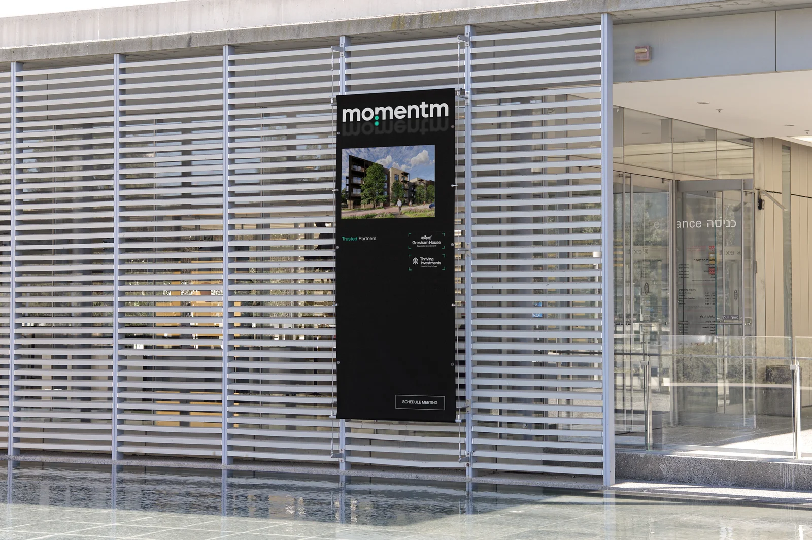A Momentm banner on a slatted building facade