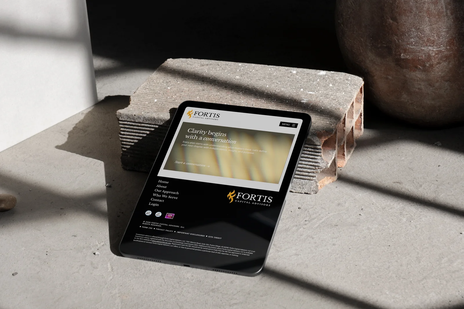 The Fortis Capital footer on a tablet, resting on a brick