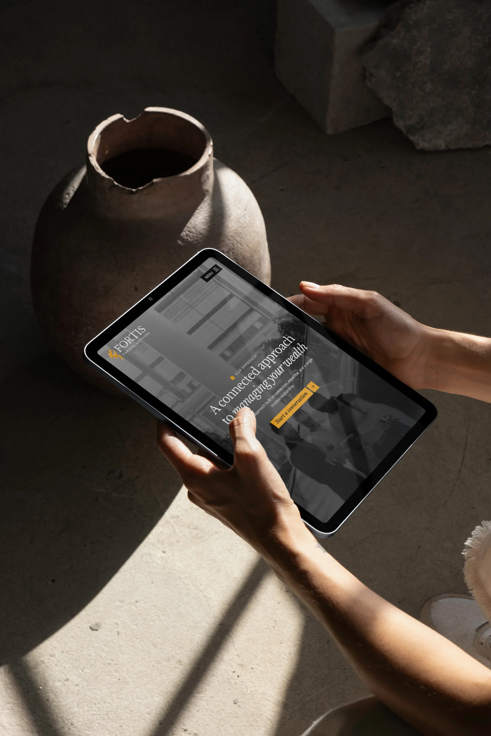The Fortis Capital approach page on a tablet, held in both hands