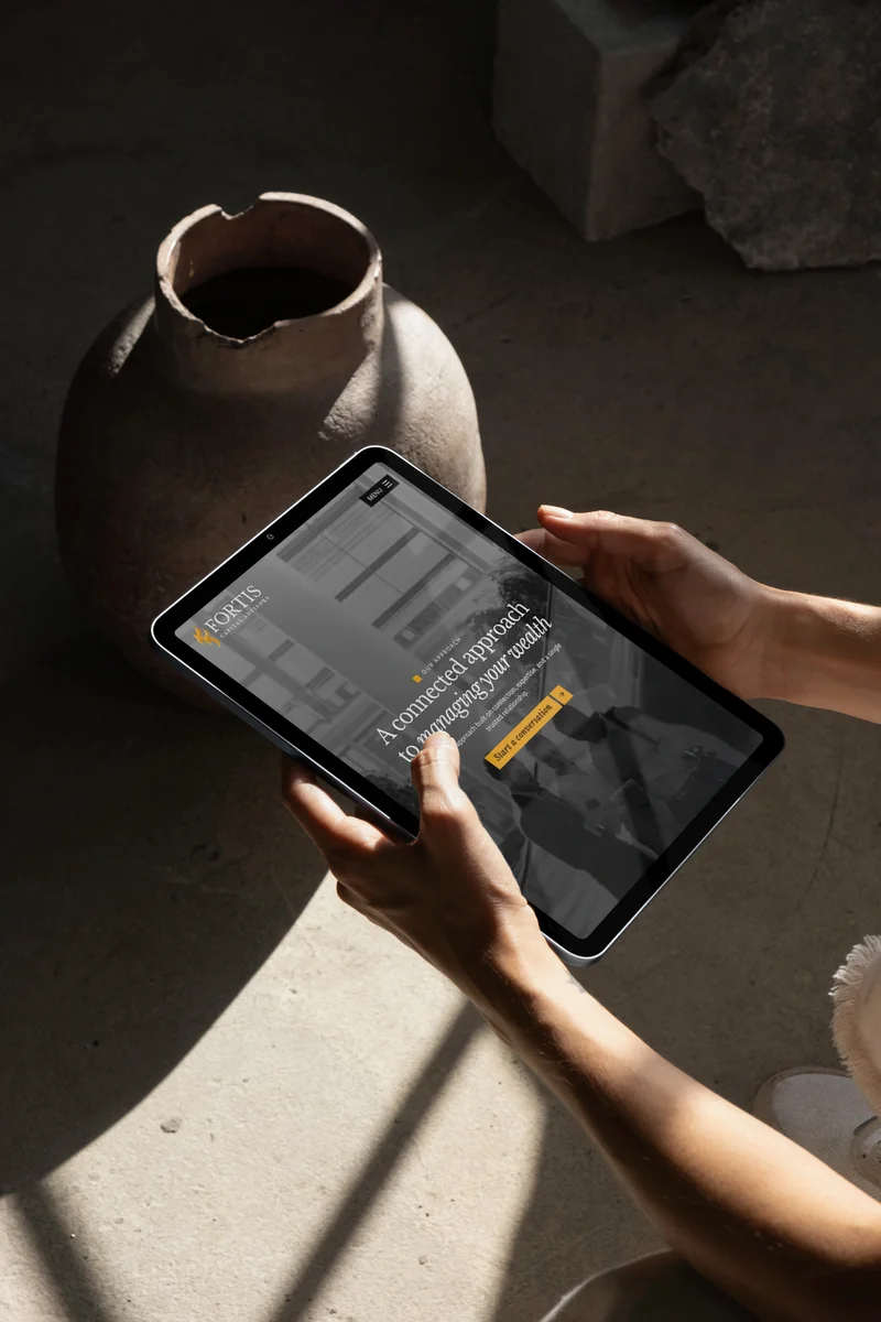 The Fortis Capital approach page on a tablet, held in both hands