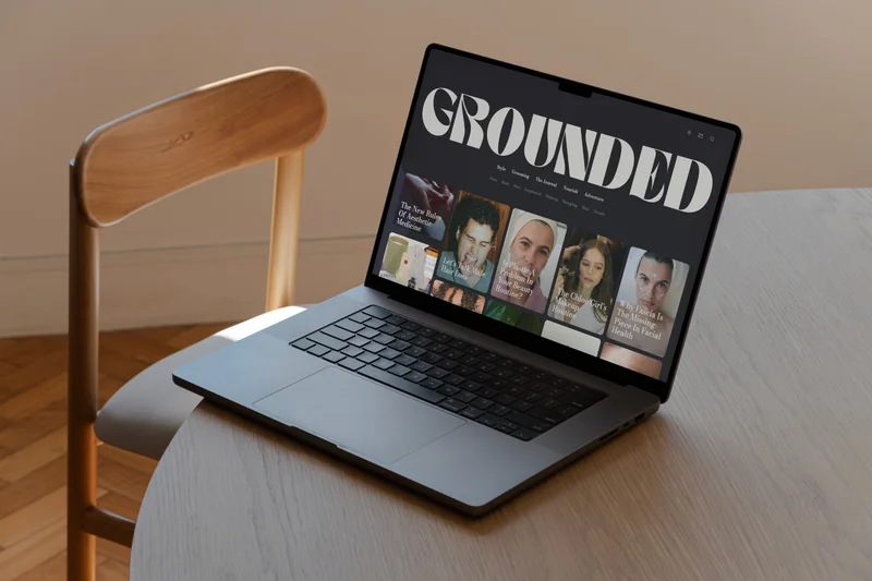 The Grounded website in dark mode on a laptop on a wooden table