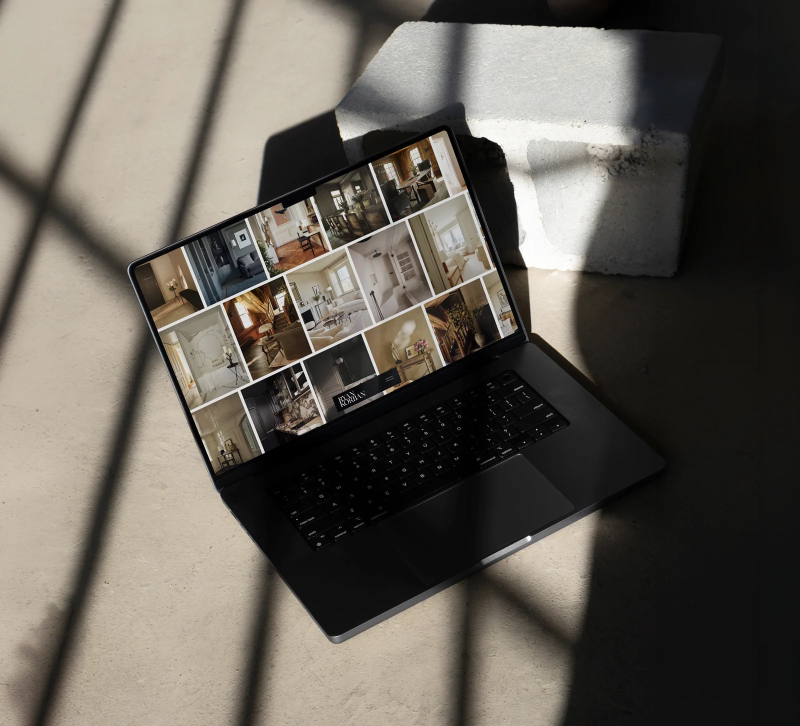 The Korban Studio projects grid on a laptop, in raking light beside a concrete block