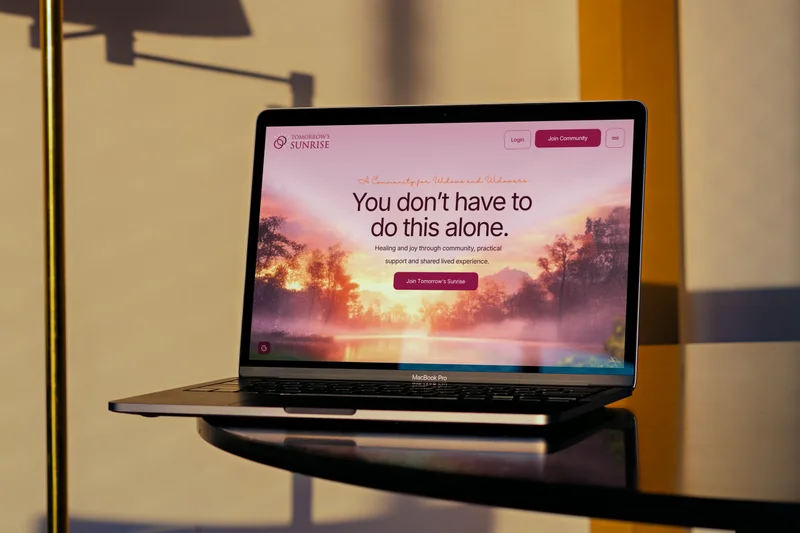 The Tomorrow’s Sunrise homepage on a laptop, on a glass table in low sunlight