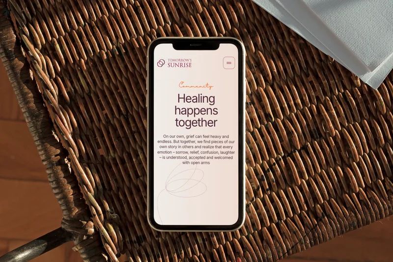 The Tomorrow’s Sunrise homepage on a phone, resting on a wicker chair