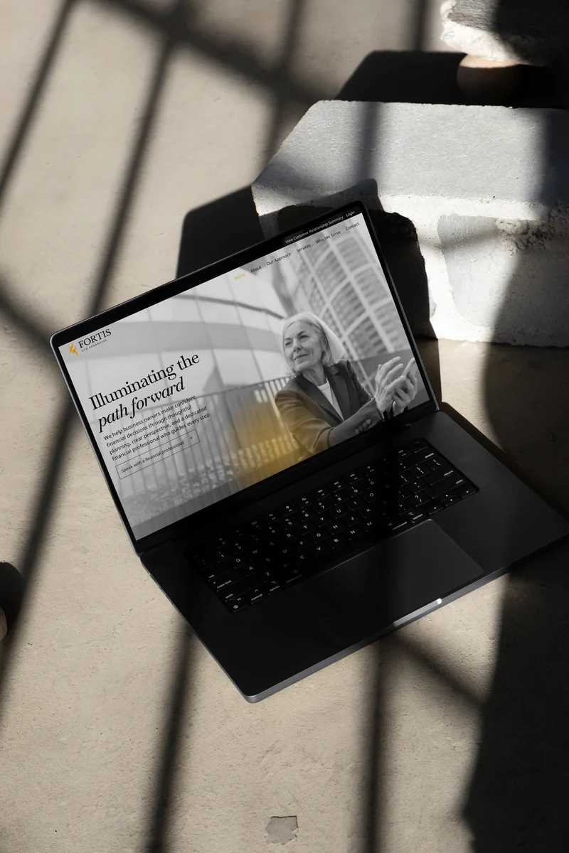 The Fortis Lux homepage on a laptop, in raking sunlight