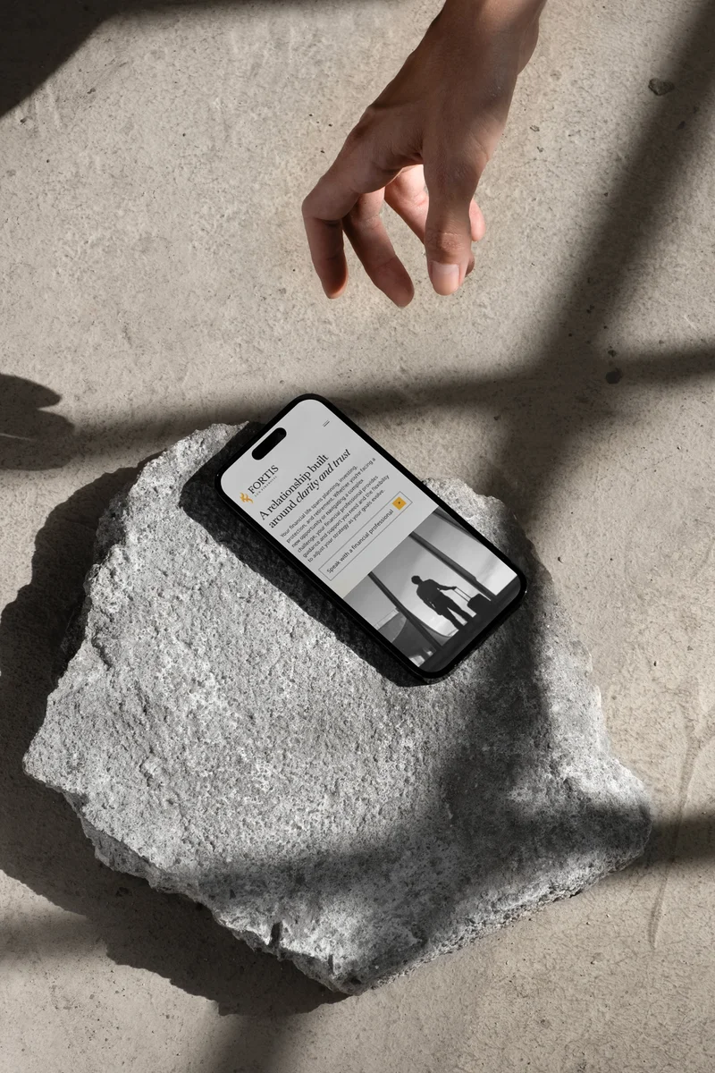 The Fortis Lux who we serve page on a phone, resting on stone