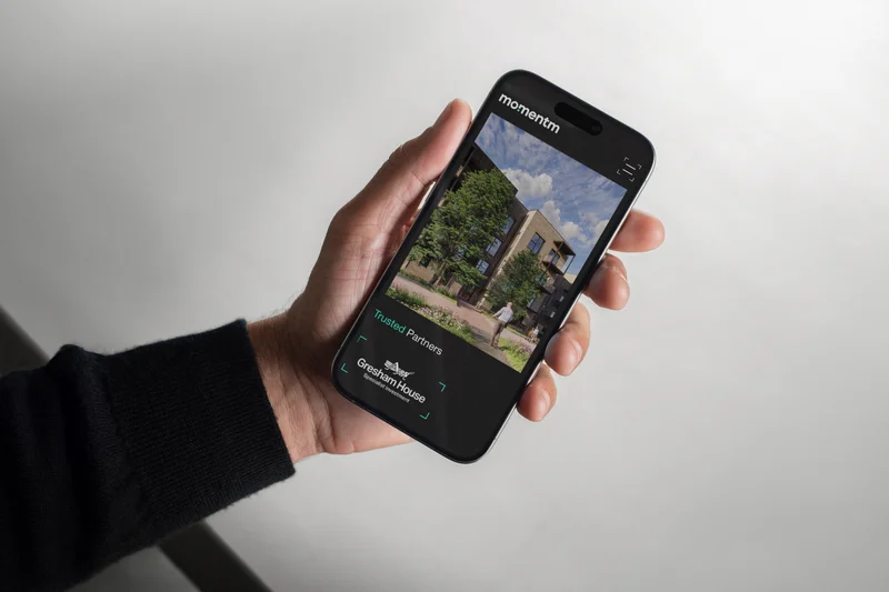 The Momentm trusted partners page on a phone, held in a hand